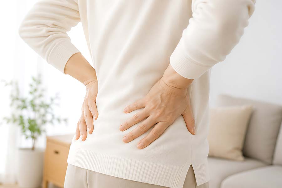 腰を押さえて腰痛に悩む女性