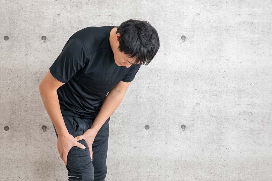 太もも部分を両手でおさえる男性